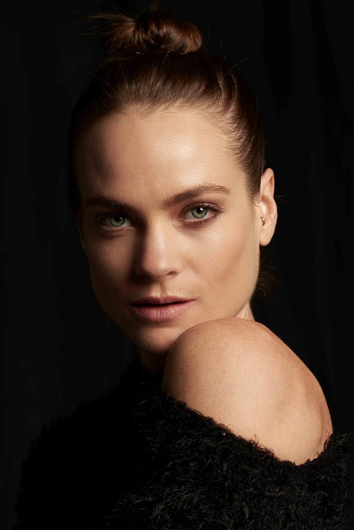 Female model with green eyes in moody beauty portrait with serious expression. Shot in studio by Stefan Venter Photography in Cape Town, South Africa.
