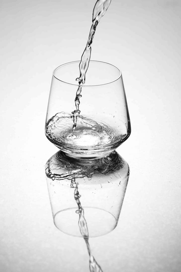 Action shot. Reflective image of water being poured into a glass. Cape Town, South Africa. Photographer Stefan Venter.
