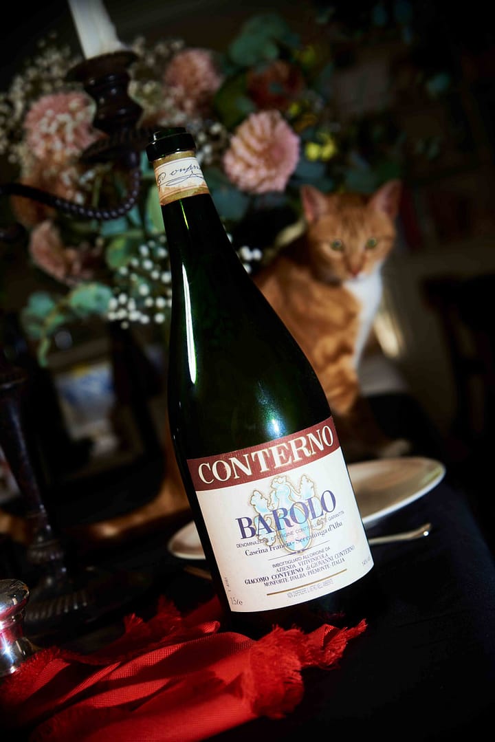 Artsy and conceptually styled picture of an Italian Barolo. Stefan Venter photography of wine bottle with a ginger cat and flowers. Barolo. Product photographer Cape Town - Stefan Venter