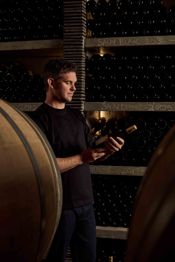 Matthew Day photographed in the Klein Constantia cellar in Cape Town by Stefan Venter Photography. Portait of wine maker, wine bottle. Barrels