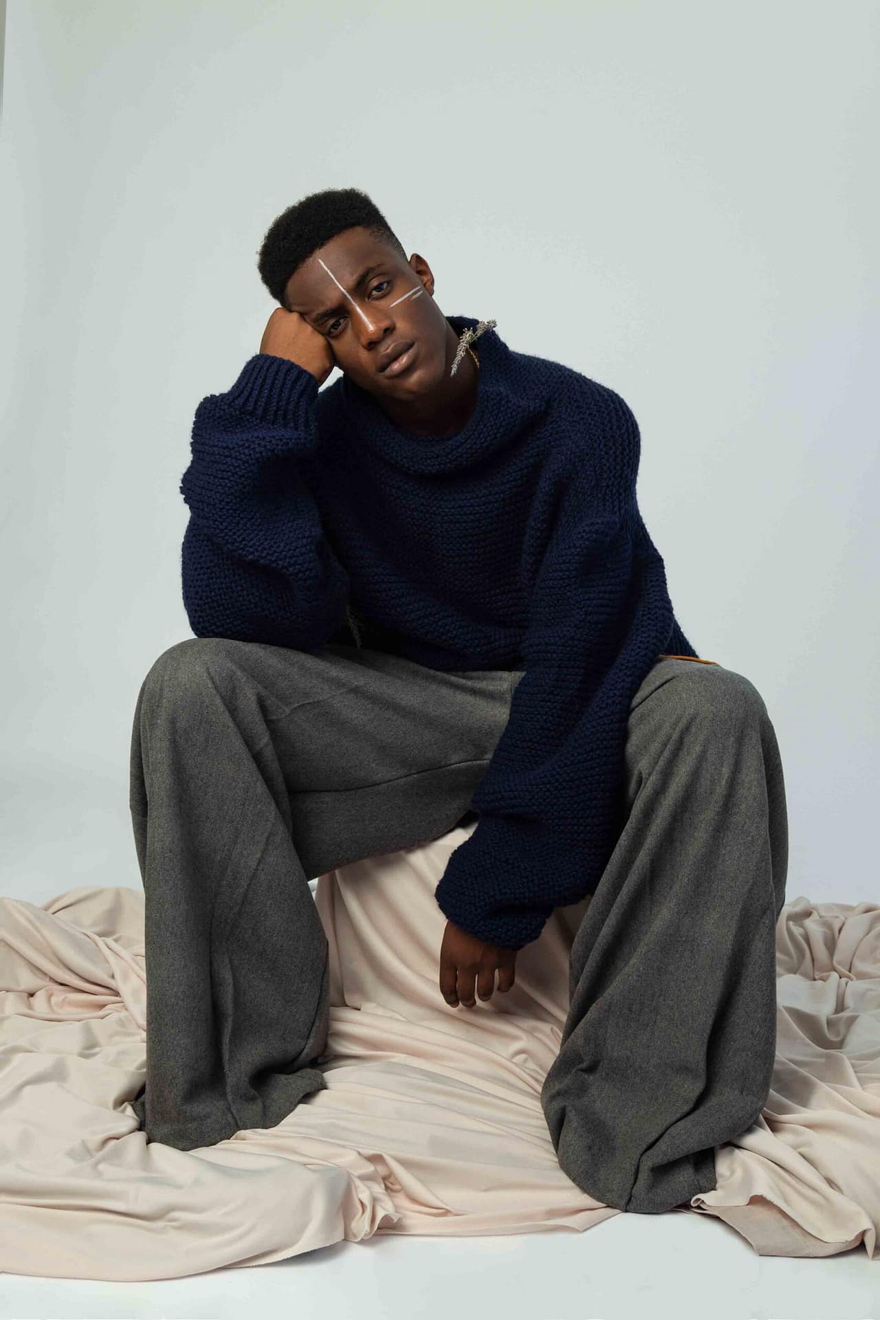 Non-functional clothing by Rustig. This shot shows details of an oversized navy knit and oversized grey pants with lavender and leather details. Worn by My Booker model, Marvellous Tshiunza.