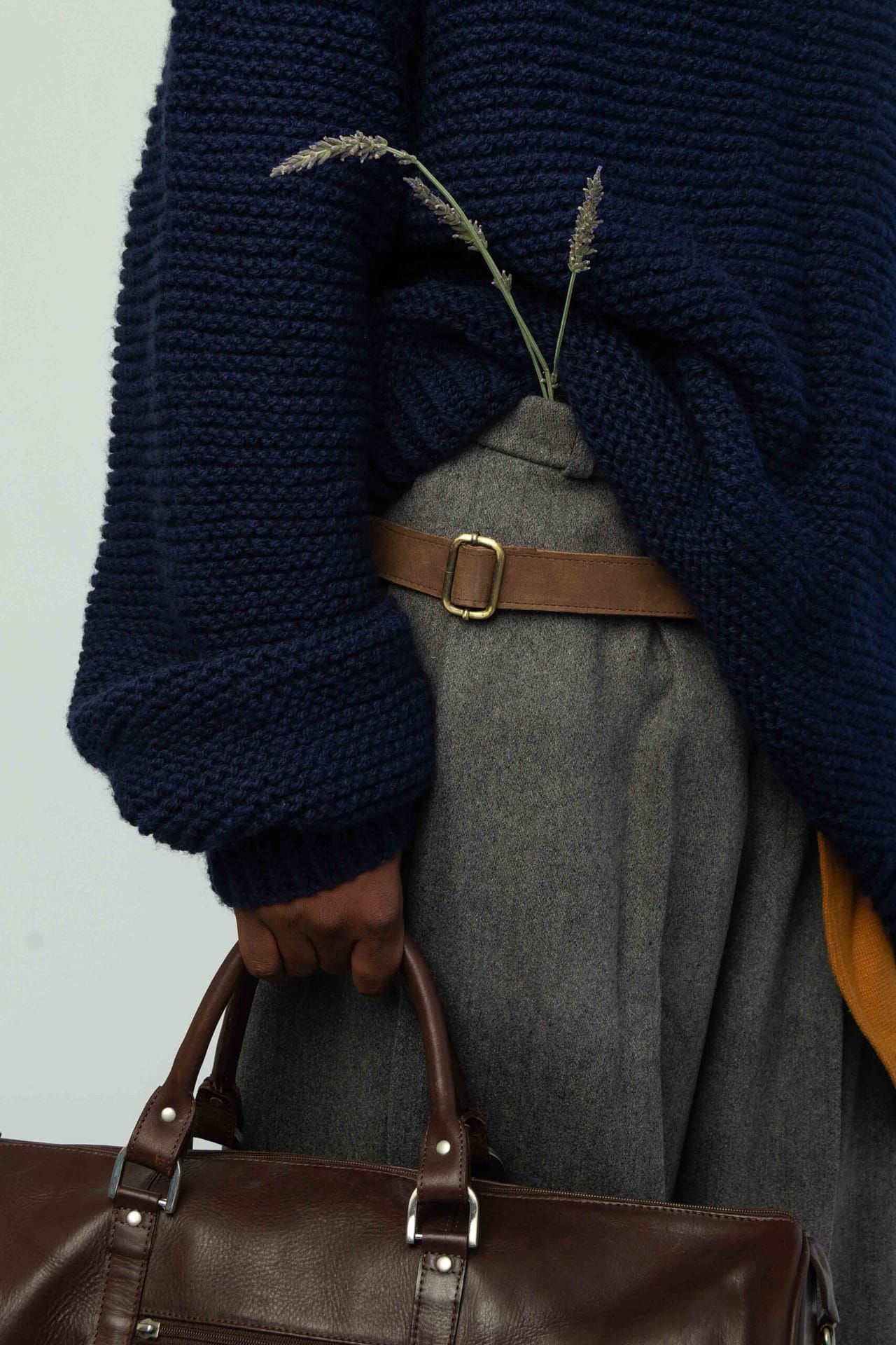 Non-functional clothing by Rustig. This shot shows details of an oversized navy knit and oversized grey pants with lavender and leather details. Worn by My Booker model, Marvellous Tshiunza.
