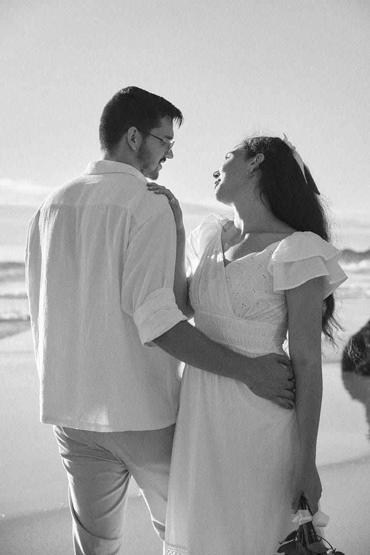 Couple on the beach for engagement shoot in Cape Town by photographer Stefan Venter. Blue sky, ocean and beach. Flowers, dress. Black and white